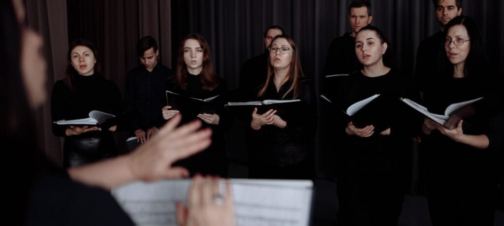 Choir singing during rehearsal with conductor leading