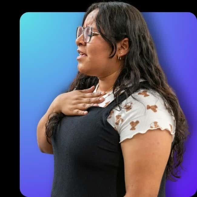 Young woman singing with hand on chest during worship